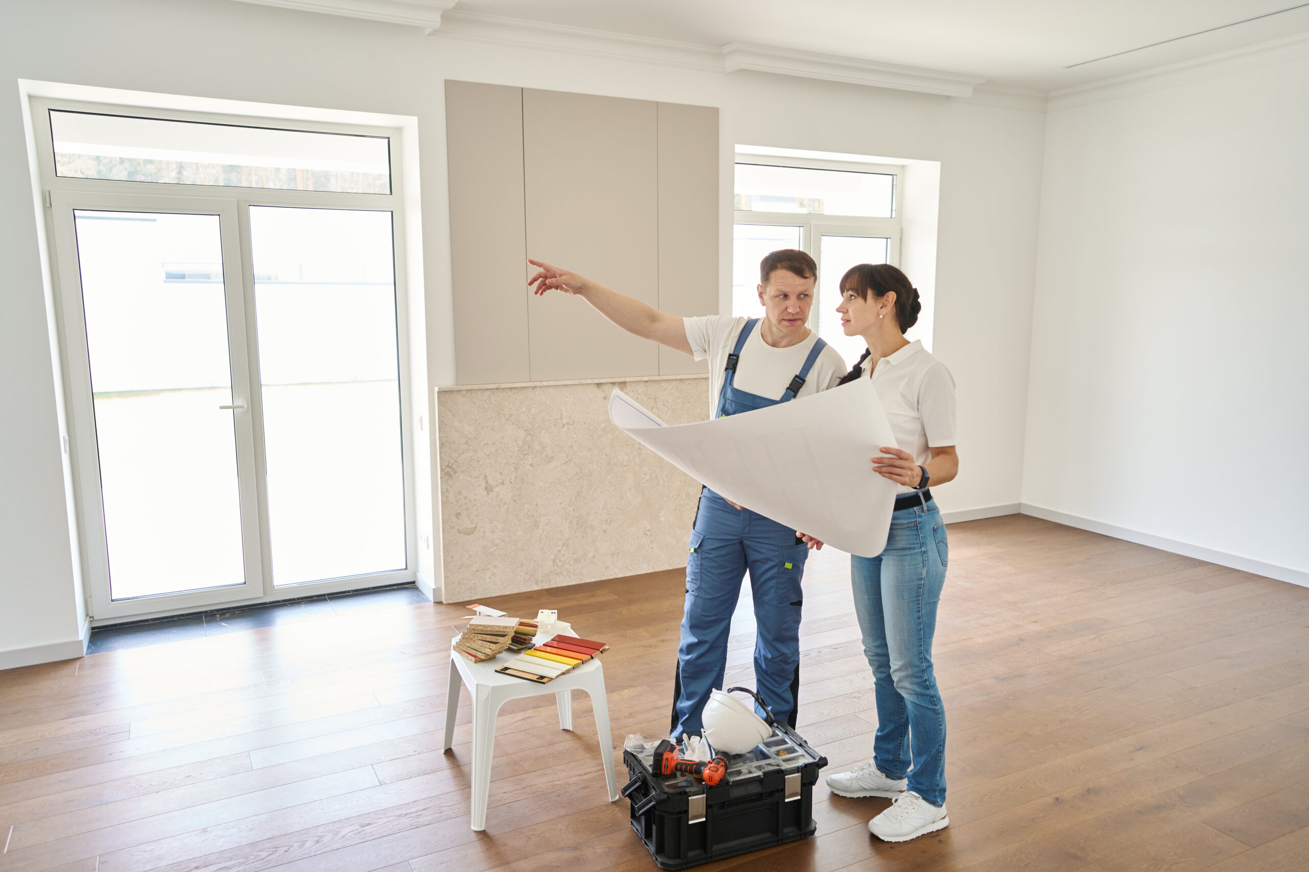 Handyman walking a room with a homeowner, pointing out areas that need repair before guests arrive