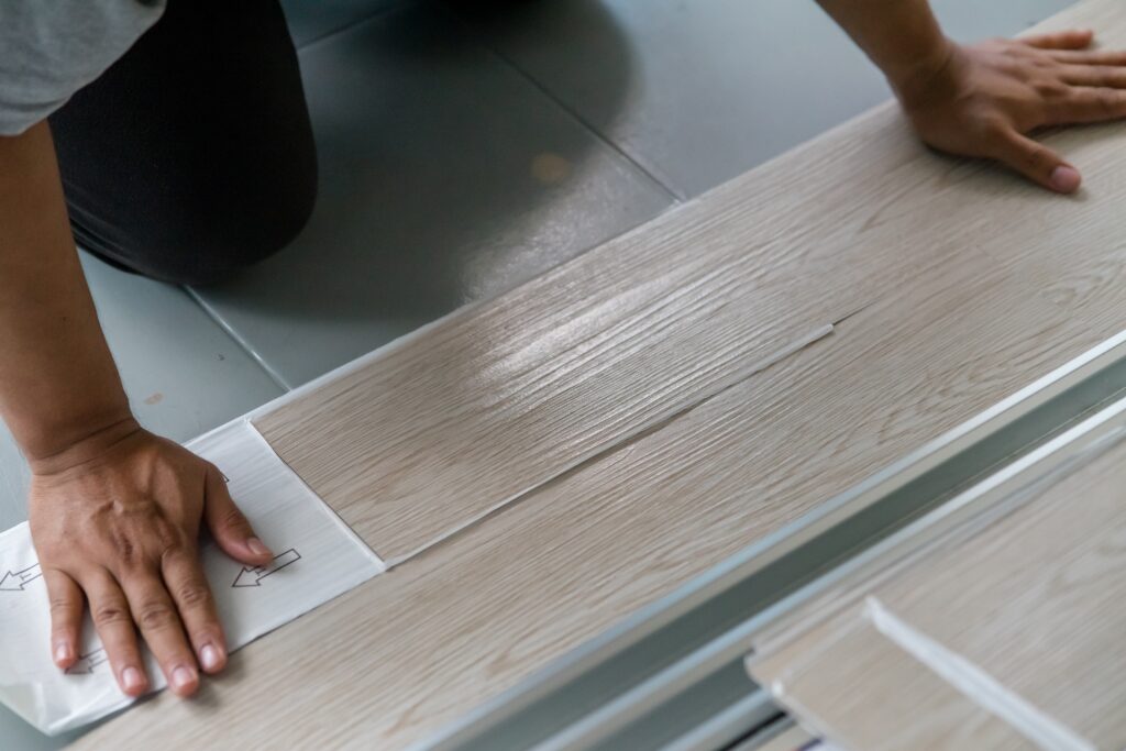 Handyman installing non-slip vinyl flooring to prevent senior falls.