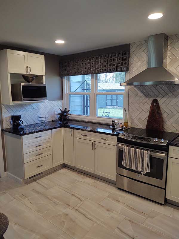 Kitchen with white shaker cabinets, dark granite counters, stainless range, chimney hood, tiled backsplash and light tile floor